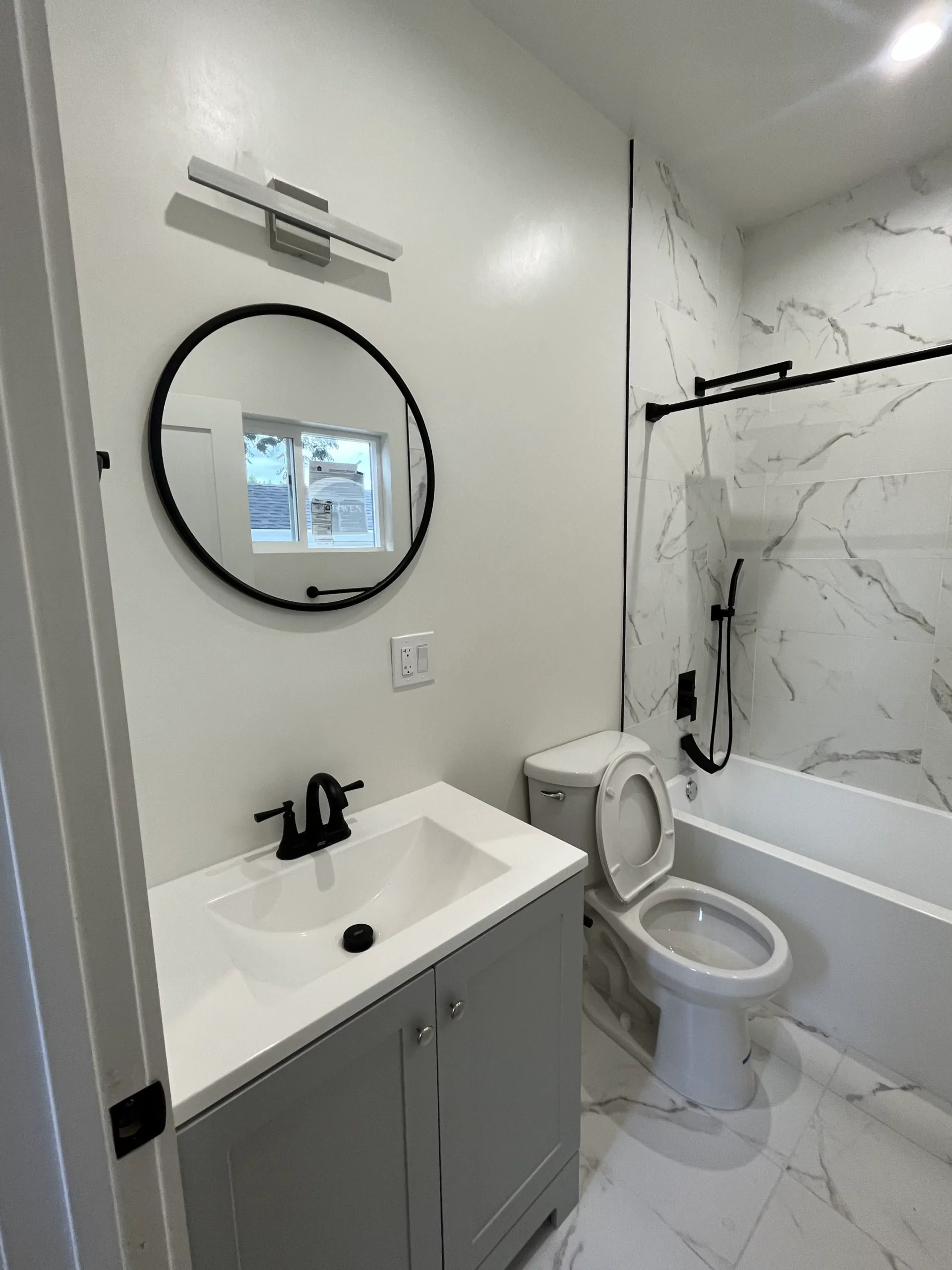 A bathroom with a toilet, sink and mirror.