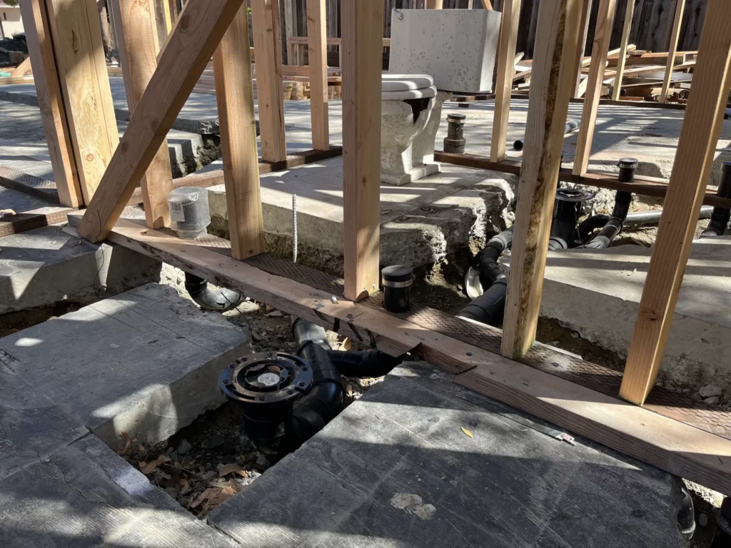 A house under construction with pipes in the ground.