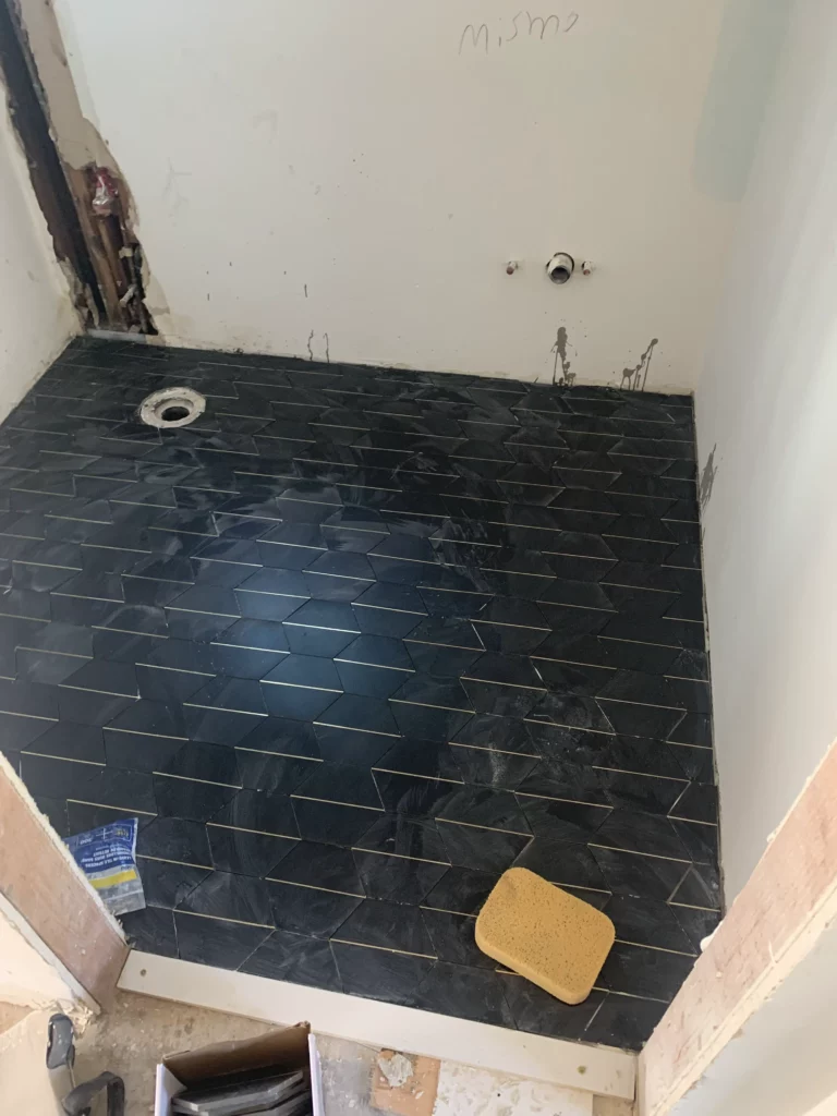 A bathroom is being remodeled with a black tile floor.