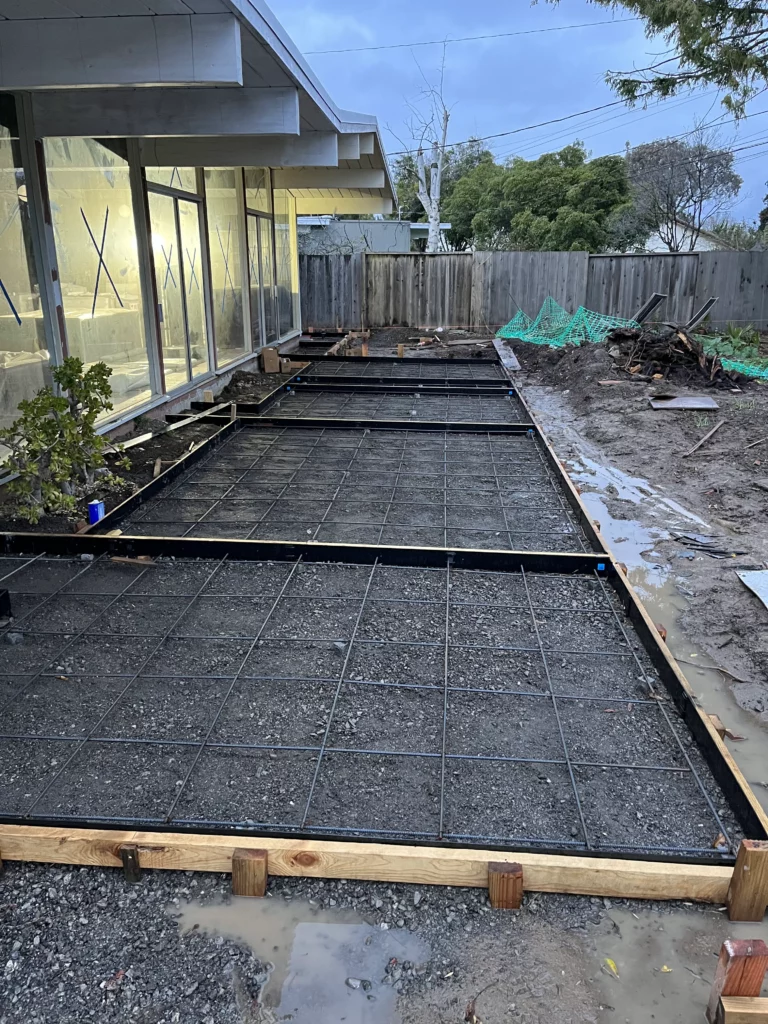 A concrete slab is being laid in a backyard.