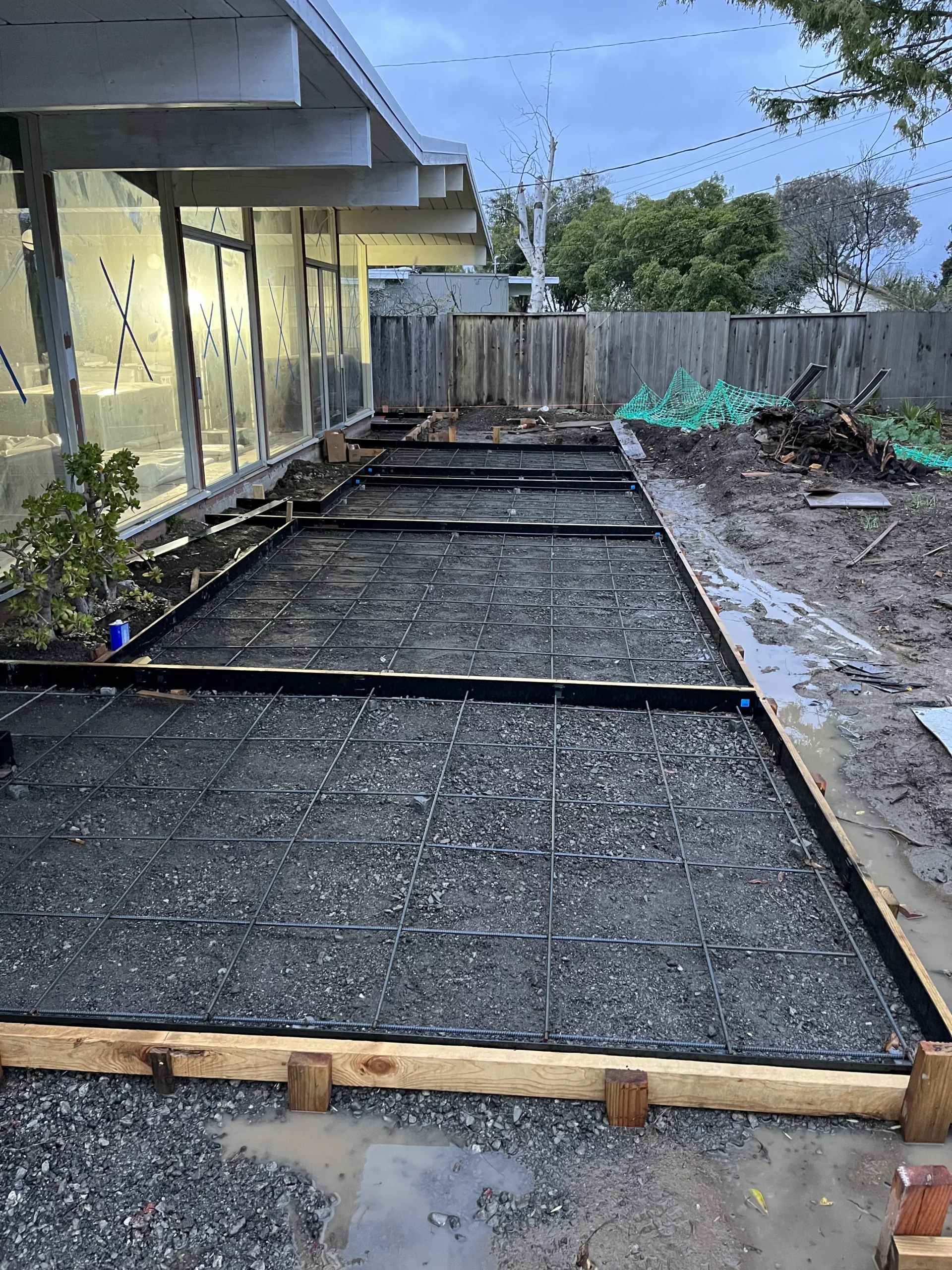 A concrete slab is being laid in a backyard.