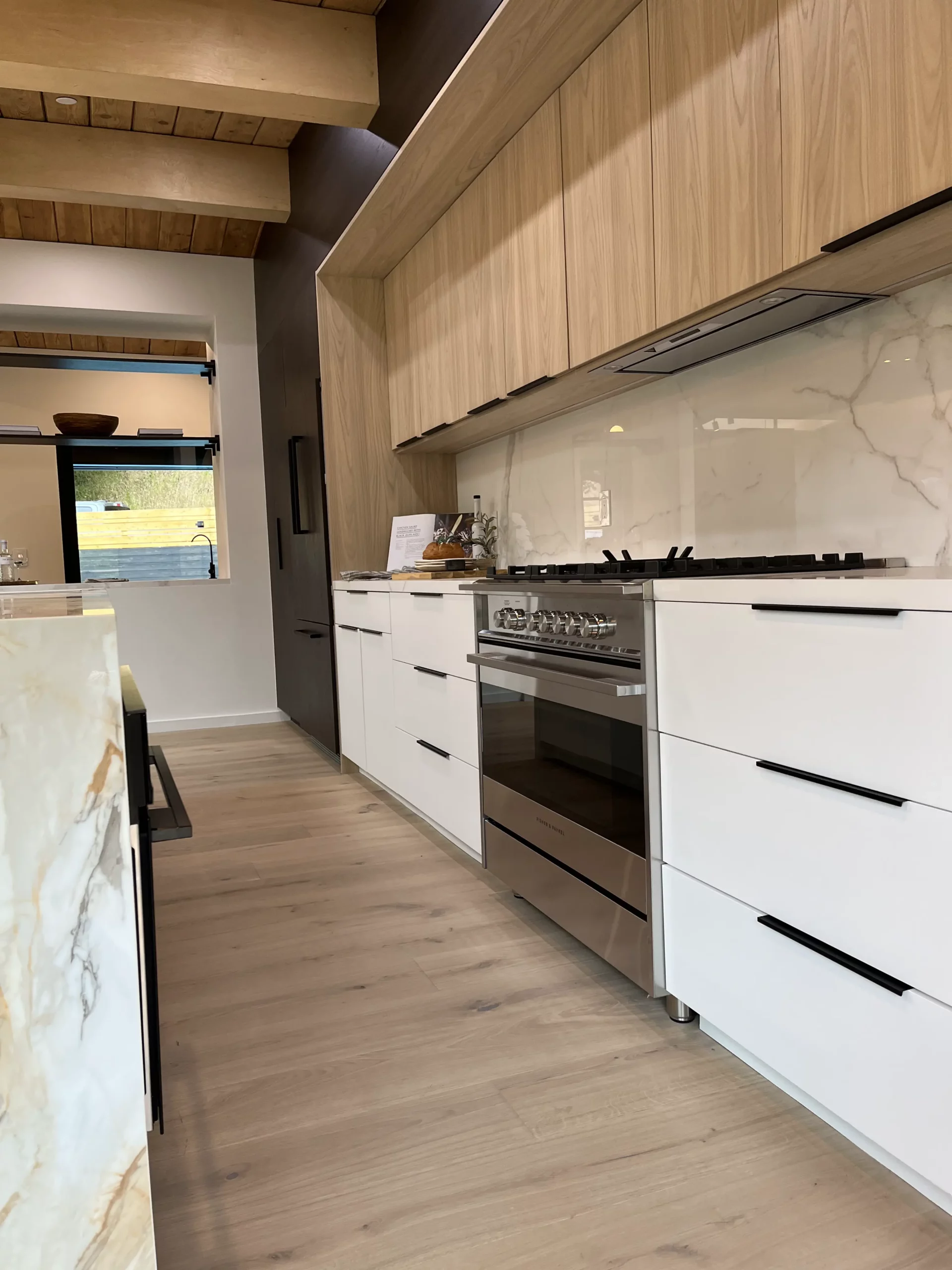 A kitchen with white cabinets and wooden floors.