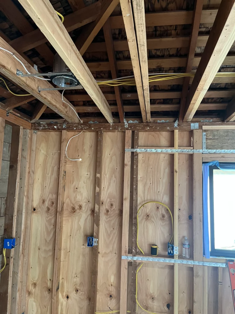 An unfinished room with wood beams and wires.