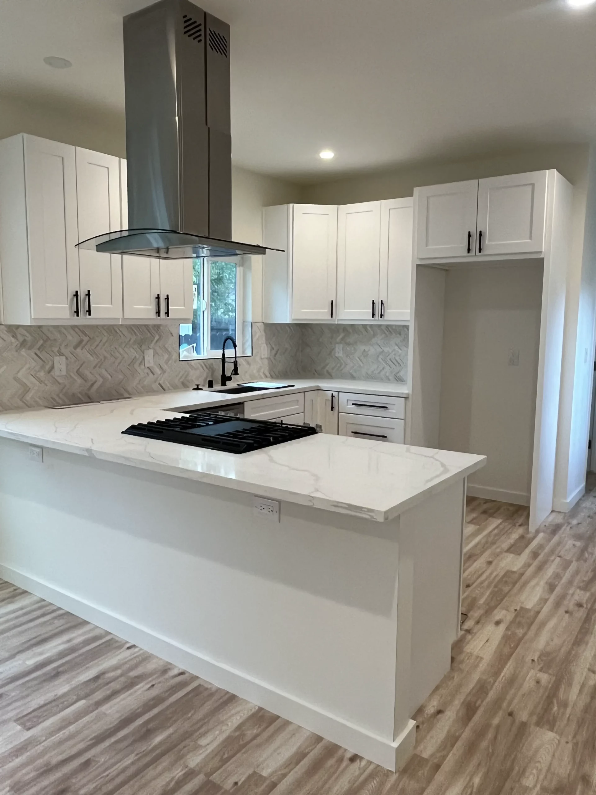 A kitchen with white cabinets and hardwood floors.