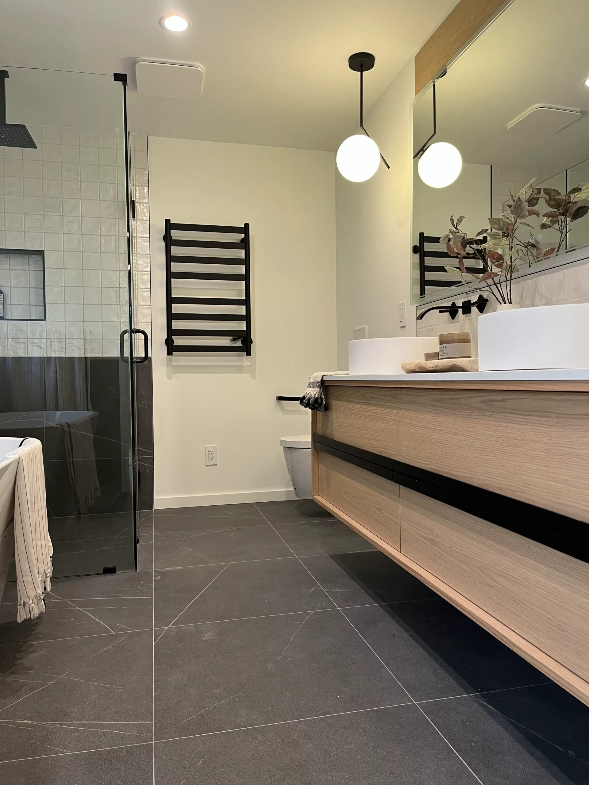 Modern bathroom remodeling project with glass shower, floating wood vanity, vessel sink, and custom interior finishes.